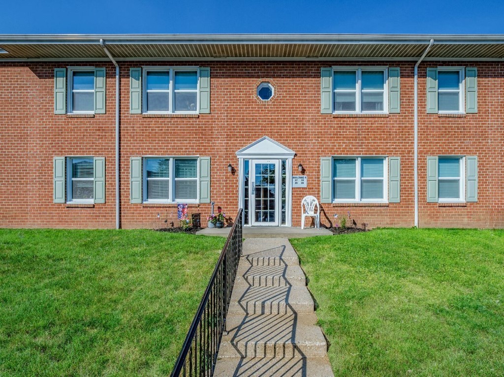 A brick building with a black fence and a green lawn in front.