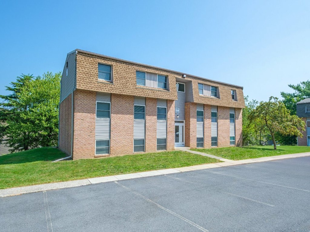 A modern brick building with a parking lot in front.