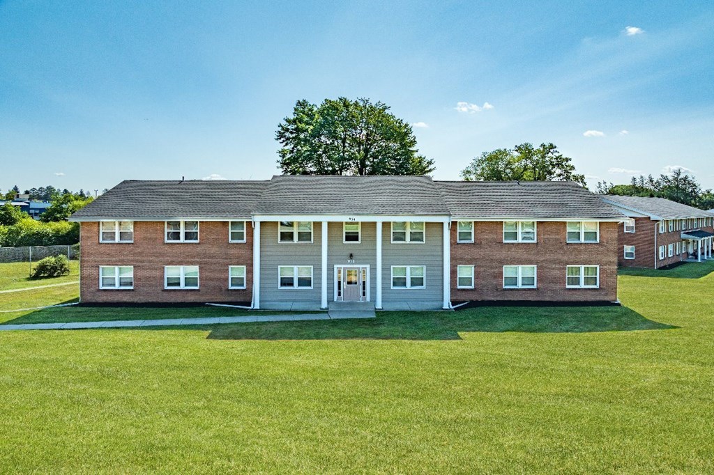 A large building with a grey roof and a green lawn in front.