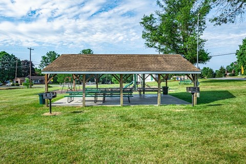 A wooden pavilion with a green lawn in front.