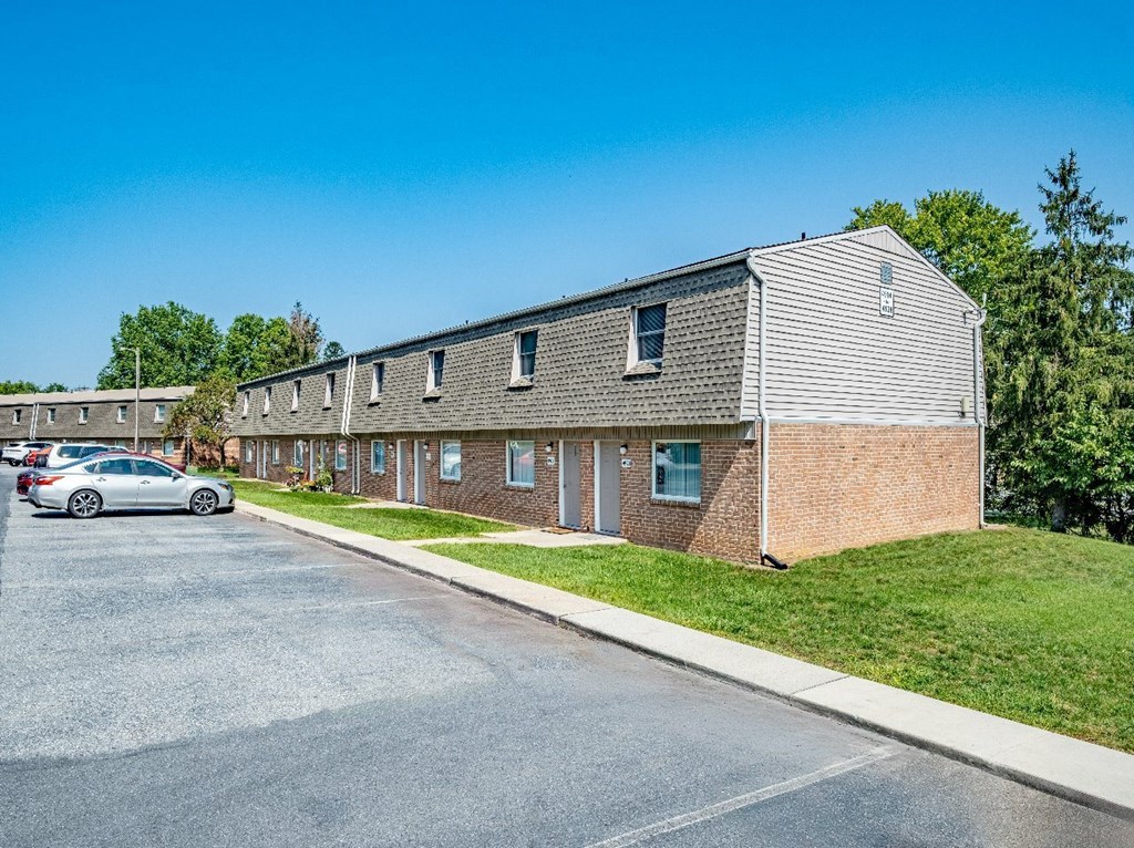 A parking lot in front of a building with a car parked.