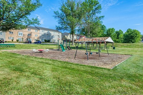 A playground with a swing set and a red slide in the foreground.