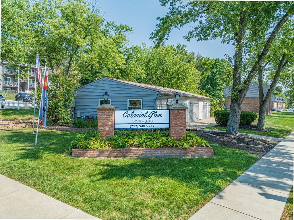 A small building with a sign that says "Colonial Heights" in front of a grassy area.