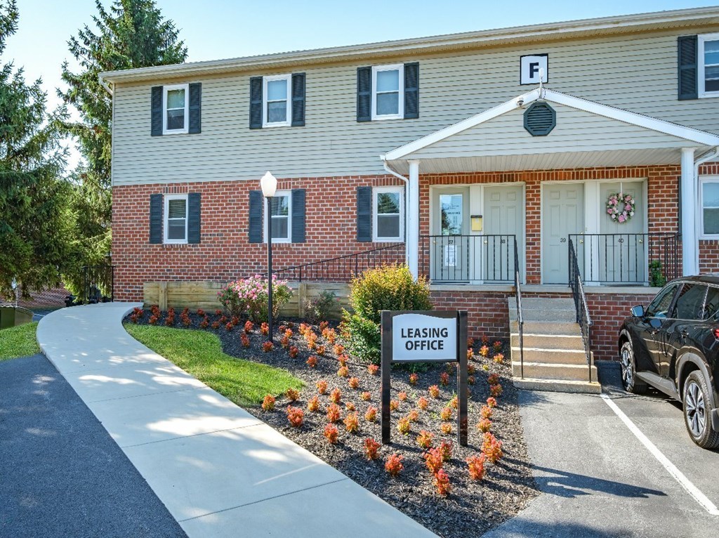A leasing office sign is displayed in front of a brick building.