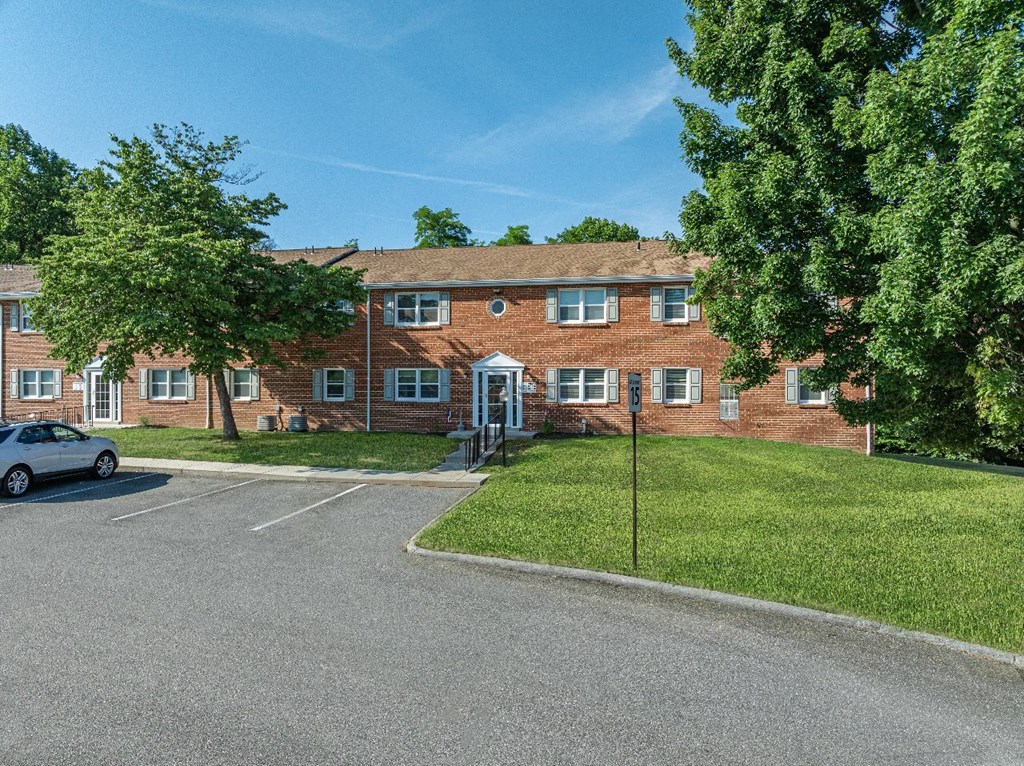 A parking lot in front of a red brick building.