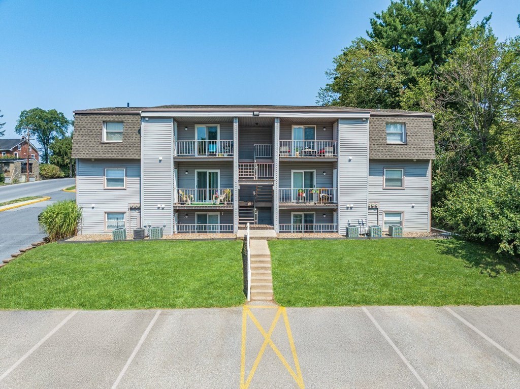 A large apartment complex with a parking lot in front.