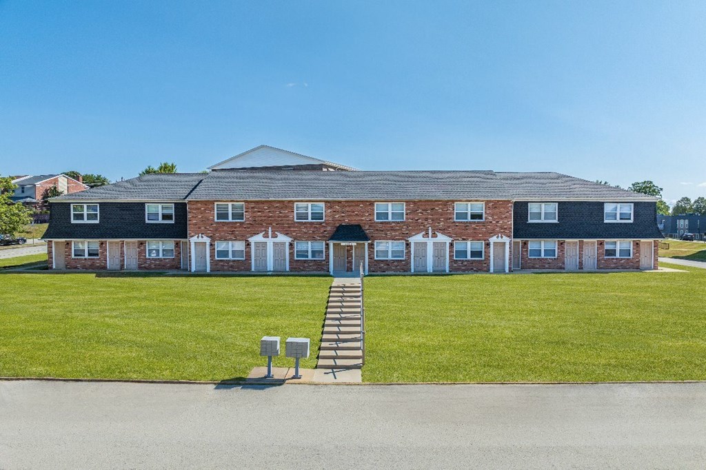 A large brick building with a grey roof and a set of stairs leading to the entrance.