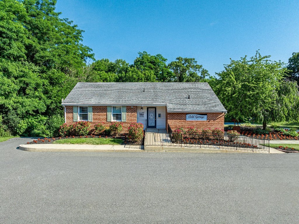 A small brick house with a sign that says "Sale" on the front.