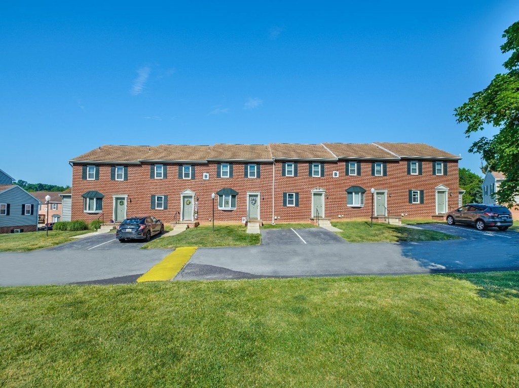 A red brick building with a parking lot in front.