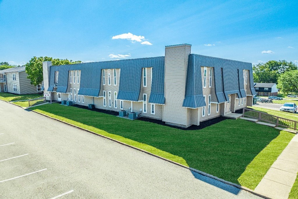 A large building with a blue roof and white walls is surrounded by a parking lot.