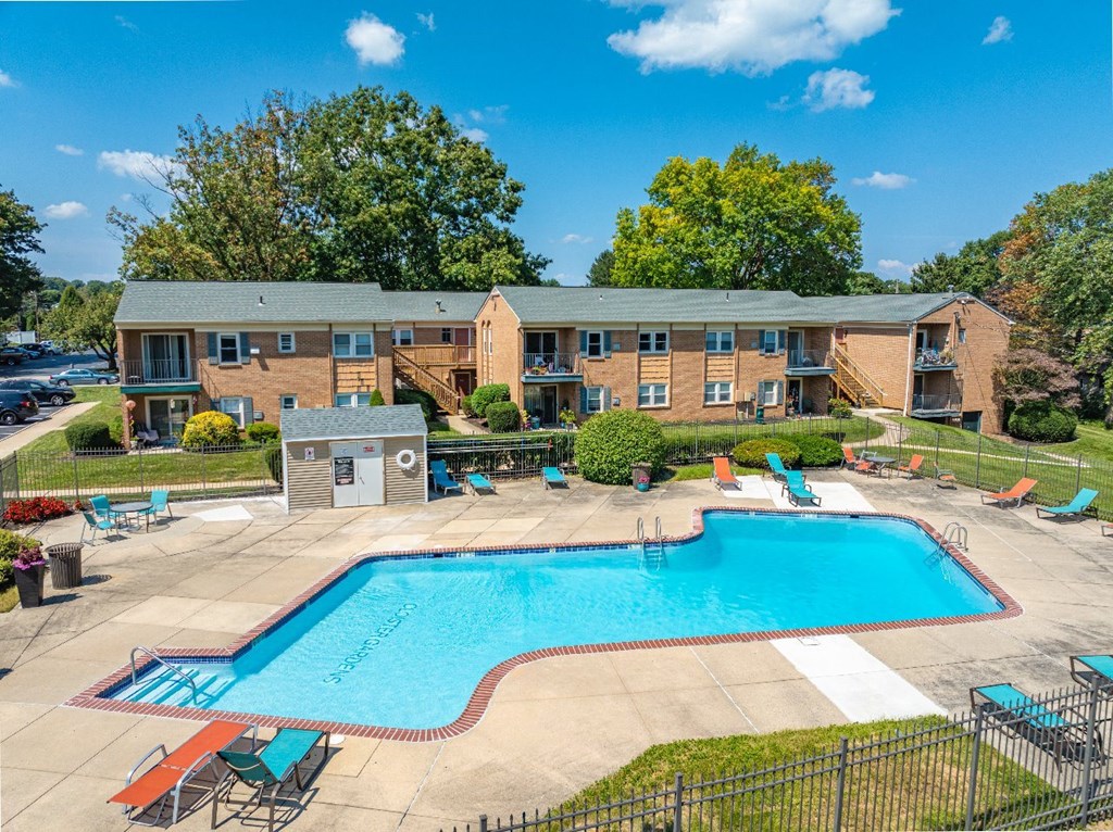 A large swimming pool in front of a building surrounded by chairs.