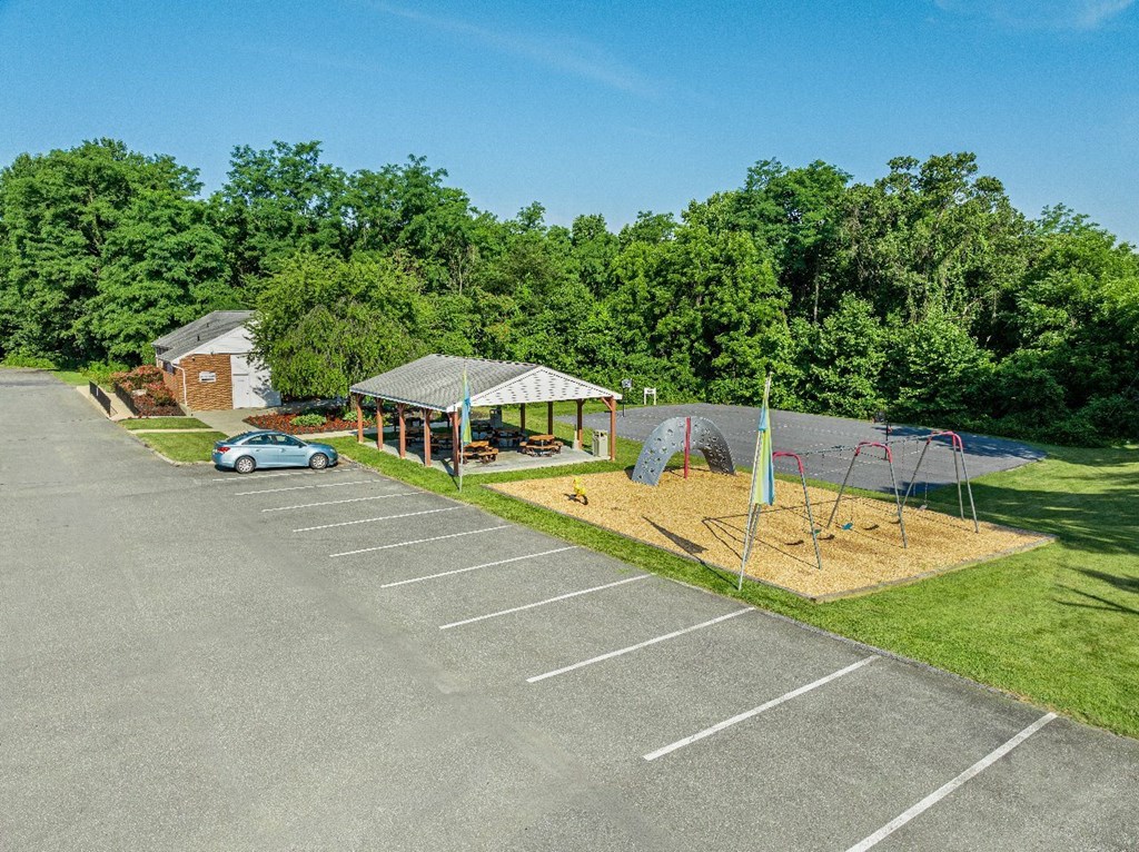 A parking lot with a playground and a building in the background.