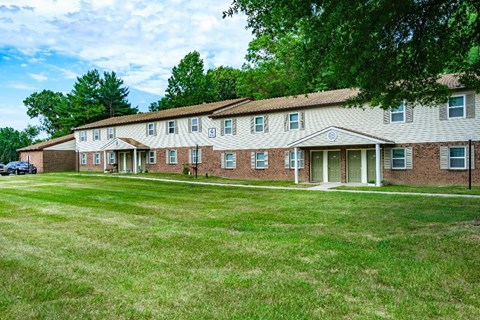 A large brick building with a green lawn in front.