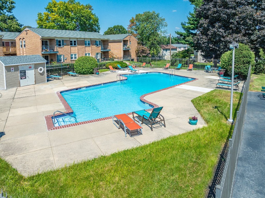 A swimming pool surrounded by chairs and a grassy area.