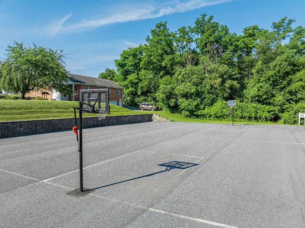 A parking lot with a signpost and trees in the background.