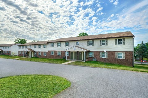 A building with a brown roof and a white door is surrounded by a grassy area.