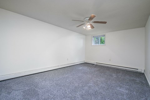 A room with a ceiling fan and carpeted floor.
