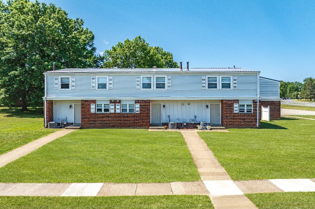 A two-story house with a white garage door and a brick chimney.