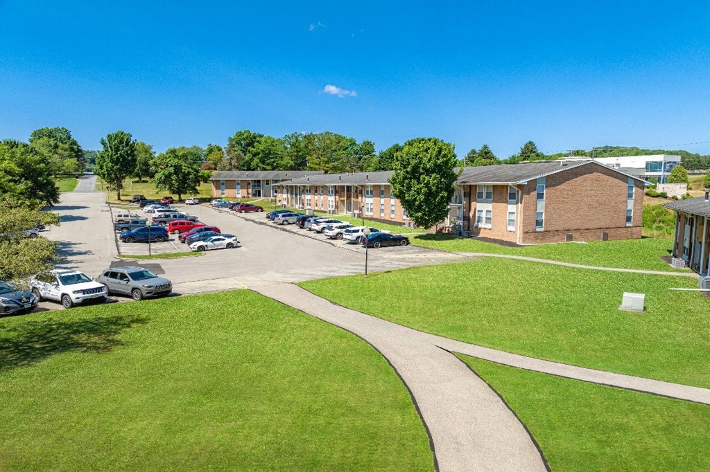 A sunny day at the school with cars parked in the lot.