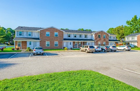 A parking lot in front of a building with cars parked.