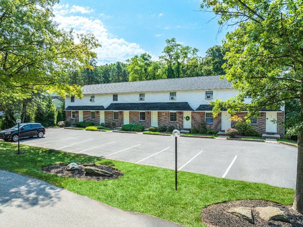 A parking lot in front of a building with a car parked in the lot.