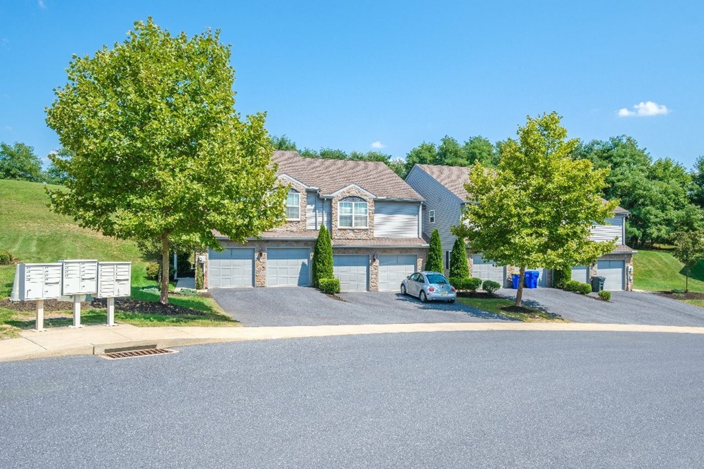 A residential street with houses and a car parked on the side.