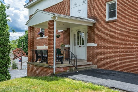 A red brick house with a white door and a small porch.