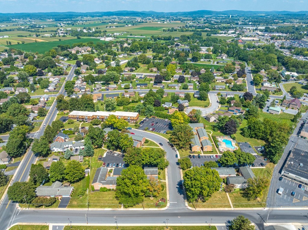 A bird's eye view of a residential area with houses, roads, and greenery.
