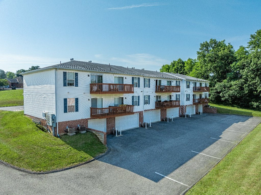 A white building with a balcony and a driveway in front.