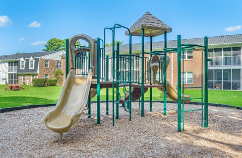 A playground with a yellow slide and green metal bars.