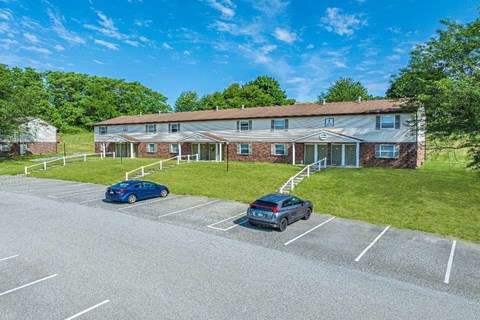 A parking lot with two cars and a building in the background.