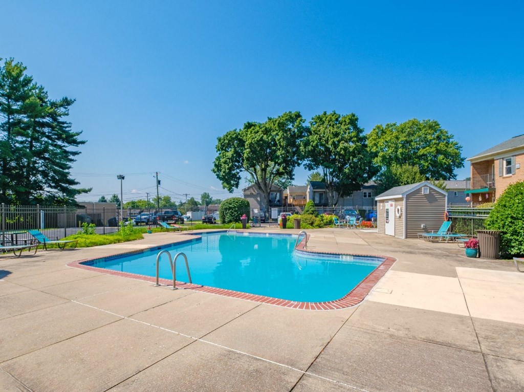 A swimming pool surrounded by a concrete patio and a residential area.