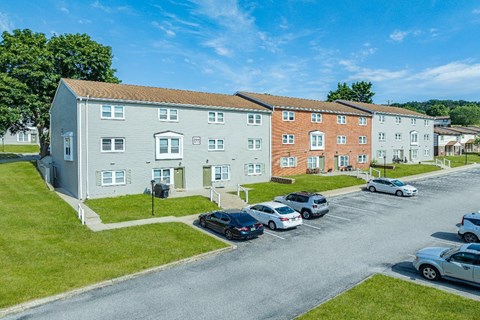A parking lot in front of a building with cars parked.