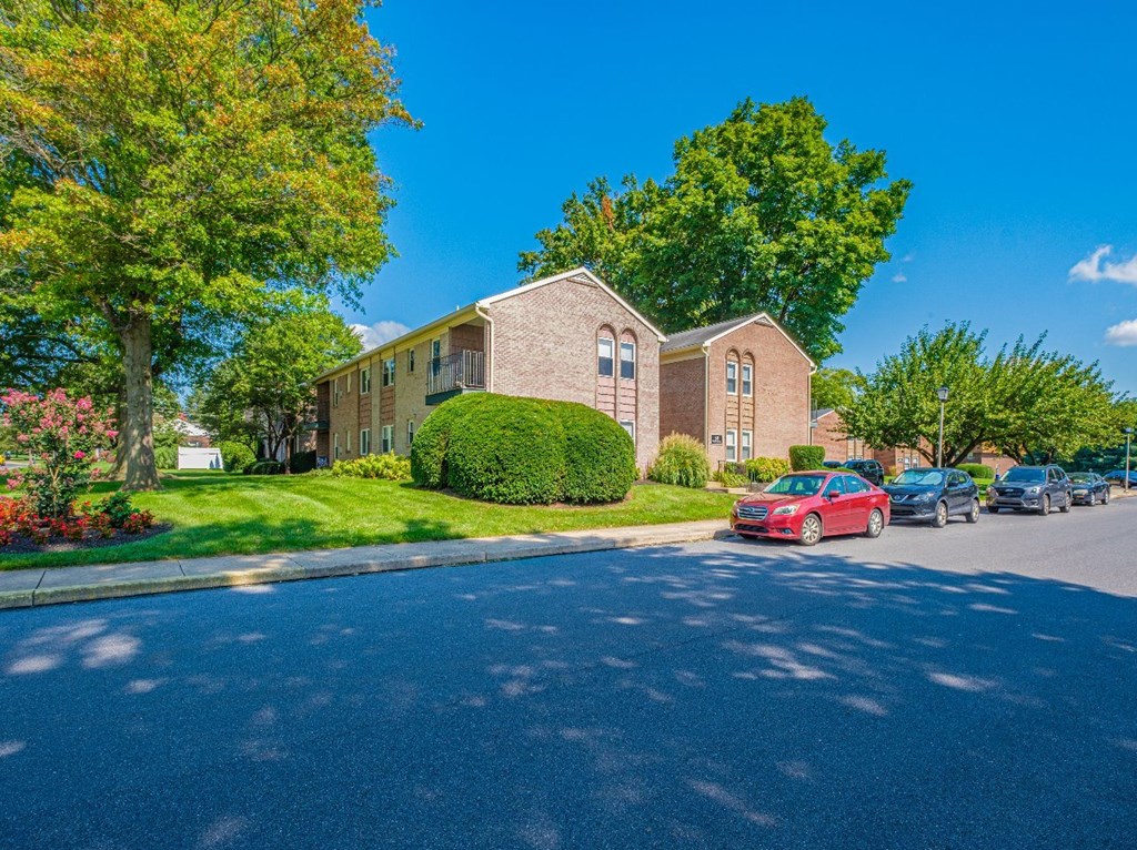 A red car is parked on the street in front of a brick building.