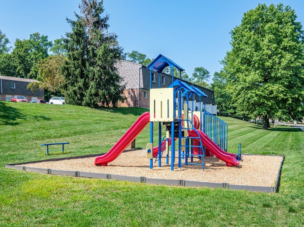 A playground with a red slide and a blue and yellow structure.