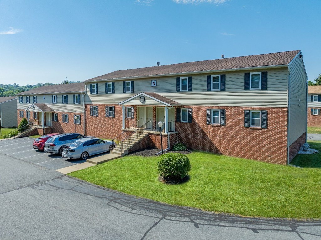 A row of houses with cars parked in front.