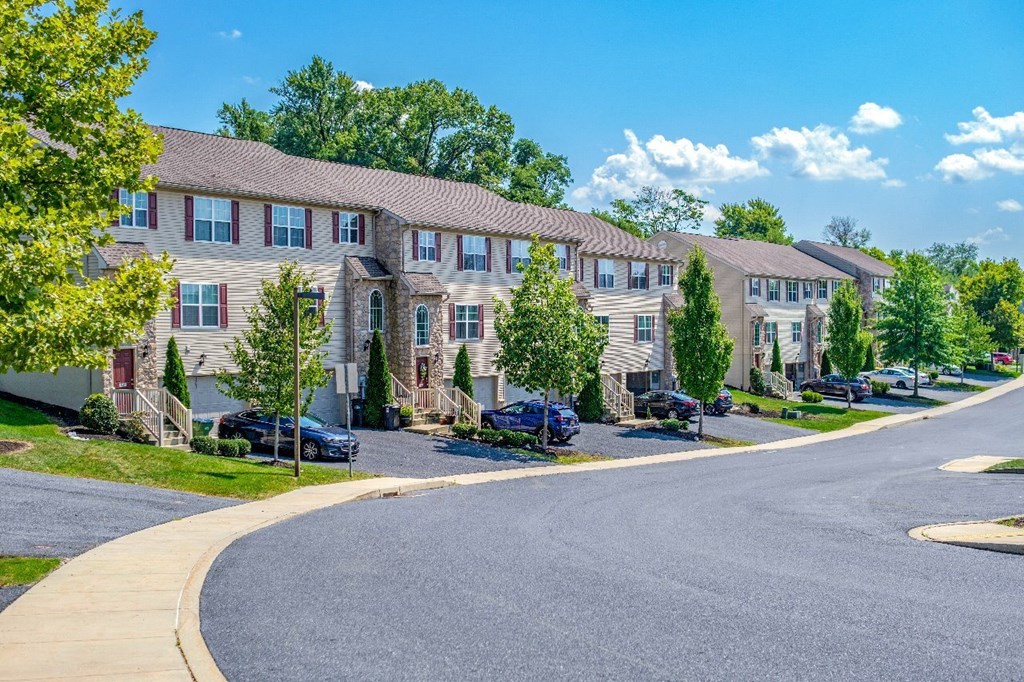 A row of houses with cars parked in front.