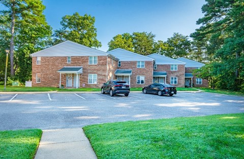 A parking lot in front of a brick building with two cars parked.