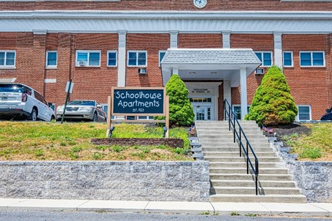 A building with a sign that says "Schoolhouse Apartments" in front of it.