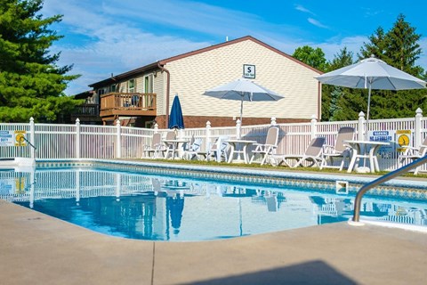 A pool with chairs and umbrellas in front of a building with a number 5 on it.