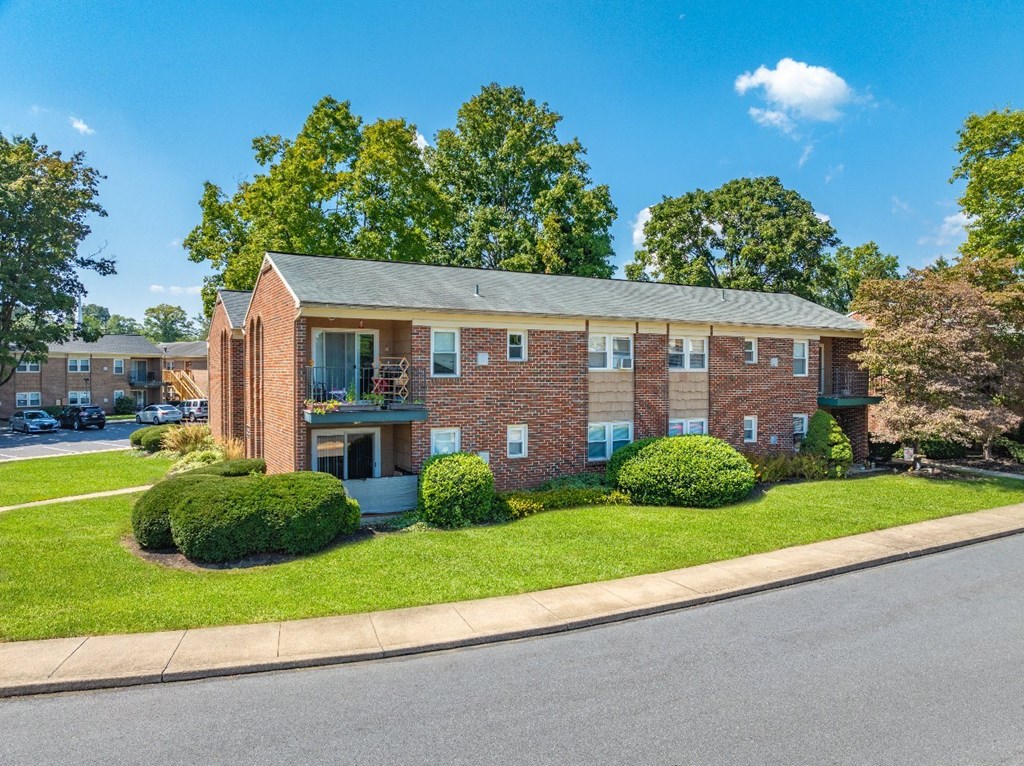 A red brick apartment building with a green lawn in front.