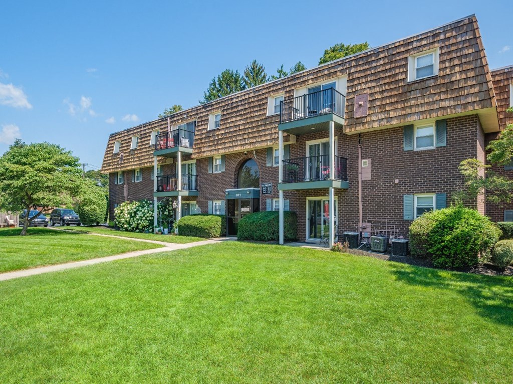 A large brick building with a green lawn in front.