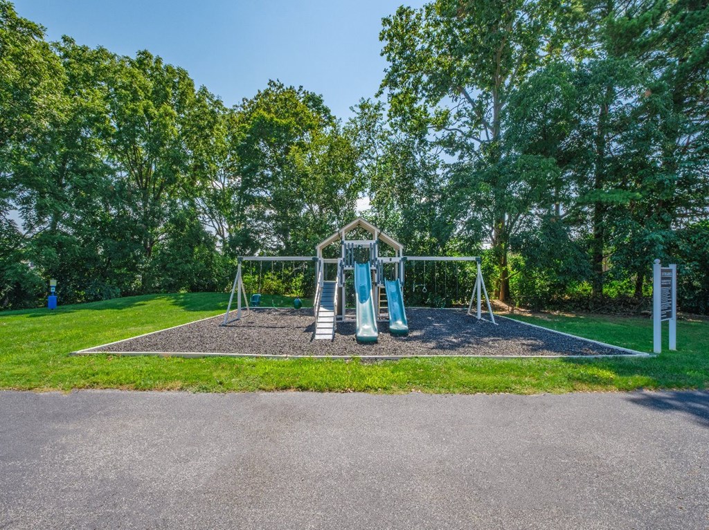 A playground with a slide and swings set in a grassy area.