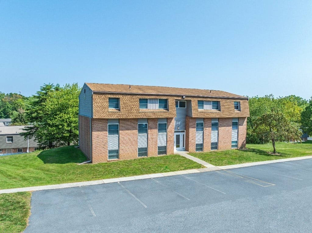 A small brick building with a parking lot in front.