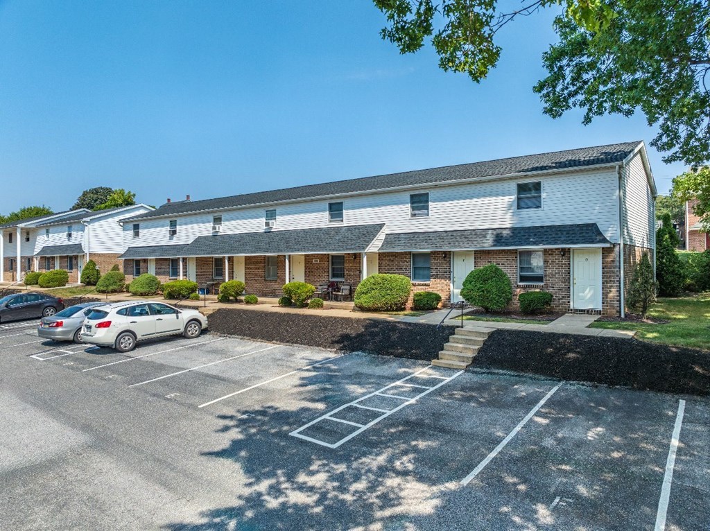 A parking lot in front of a building with cars parked.