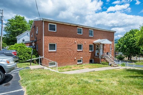 A red brick house with a white awning and a car parked in front.