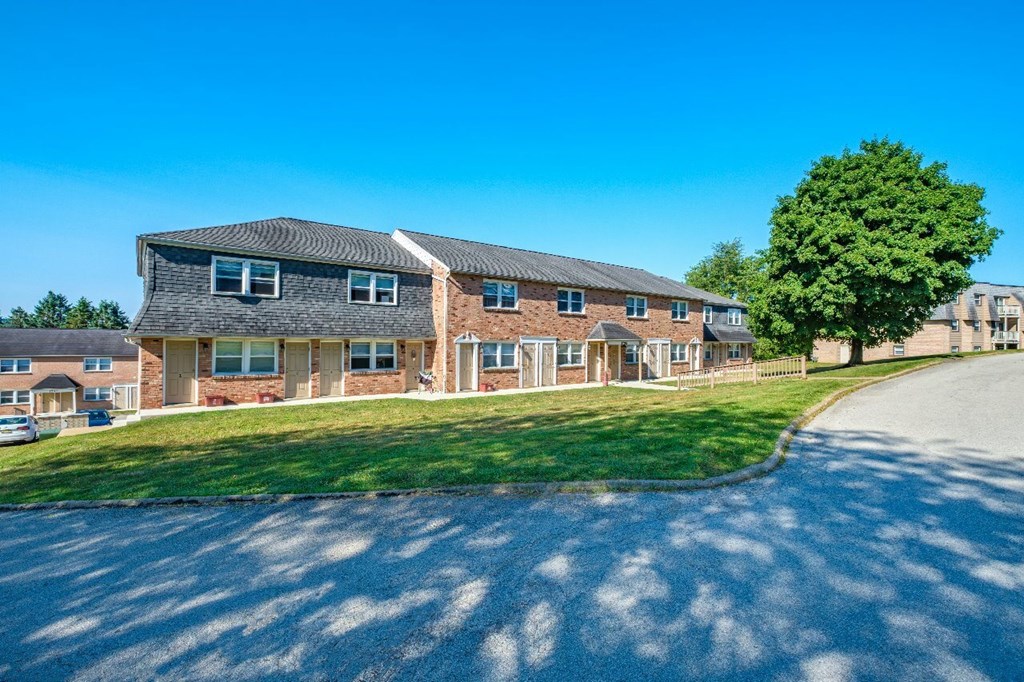 A large building with a grey roof and a driveway in front.