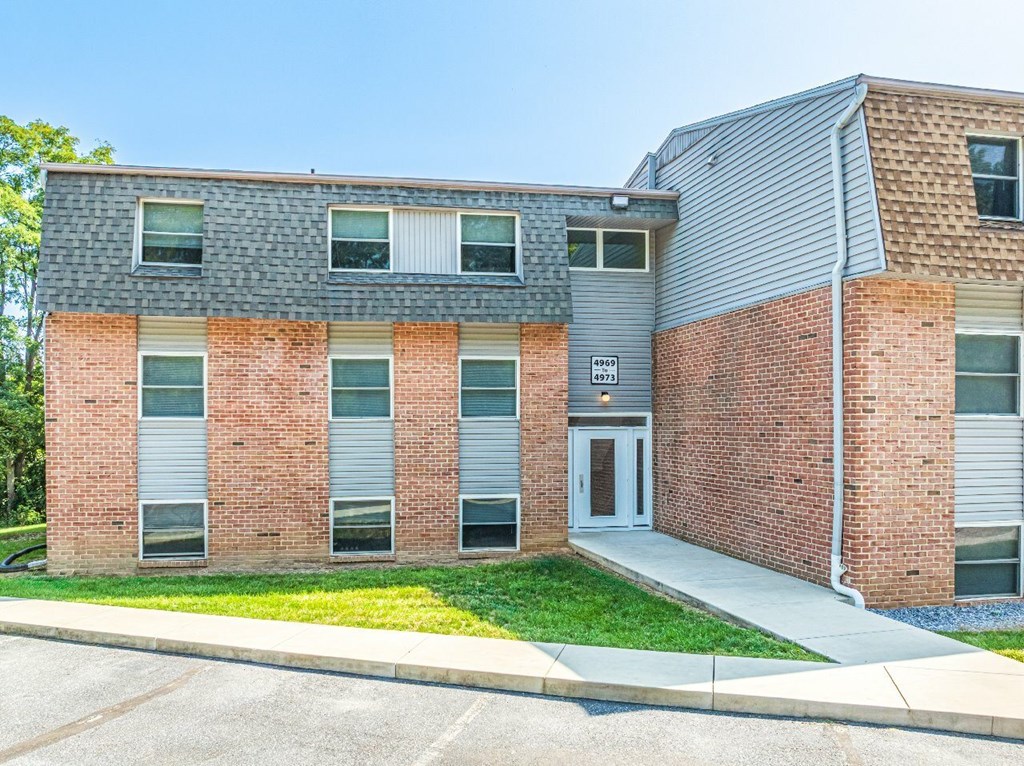 A two-story brick building with a grey roof and a white door.