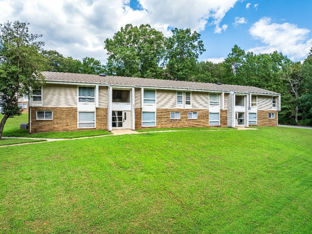 A large grassy area in front of a brick apartment building.