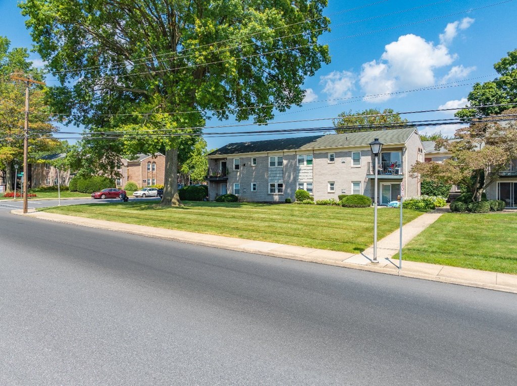 A street view with a red car parked on the side of the road.